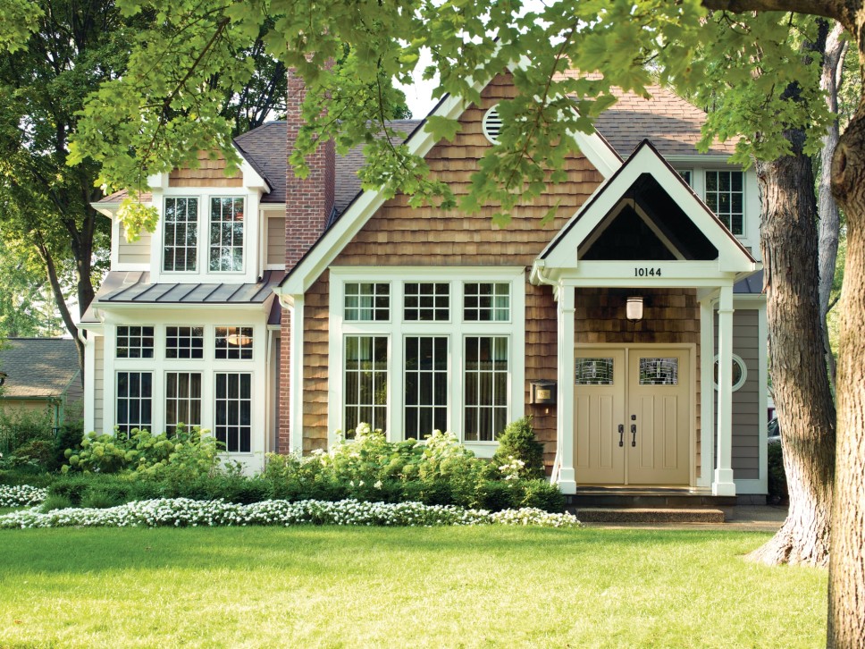 Exterior of a home with siding and brick that has large, tall energy efficient windows throughout